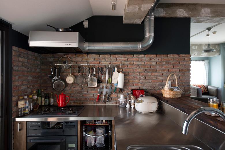 キッチンの側面はコンクリートブロック。レンジフードの配管もあえて見せるデザインに。普段使いの調理器具は、壁面に吊るしておく見せる収納に