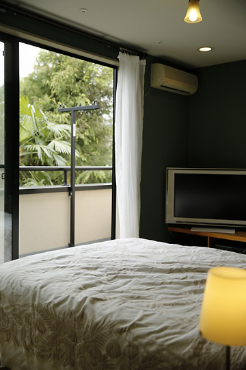 「室内も窓からの緑も…　色彩あふれる毎日を暮らす」の寝室