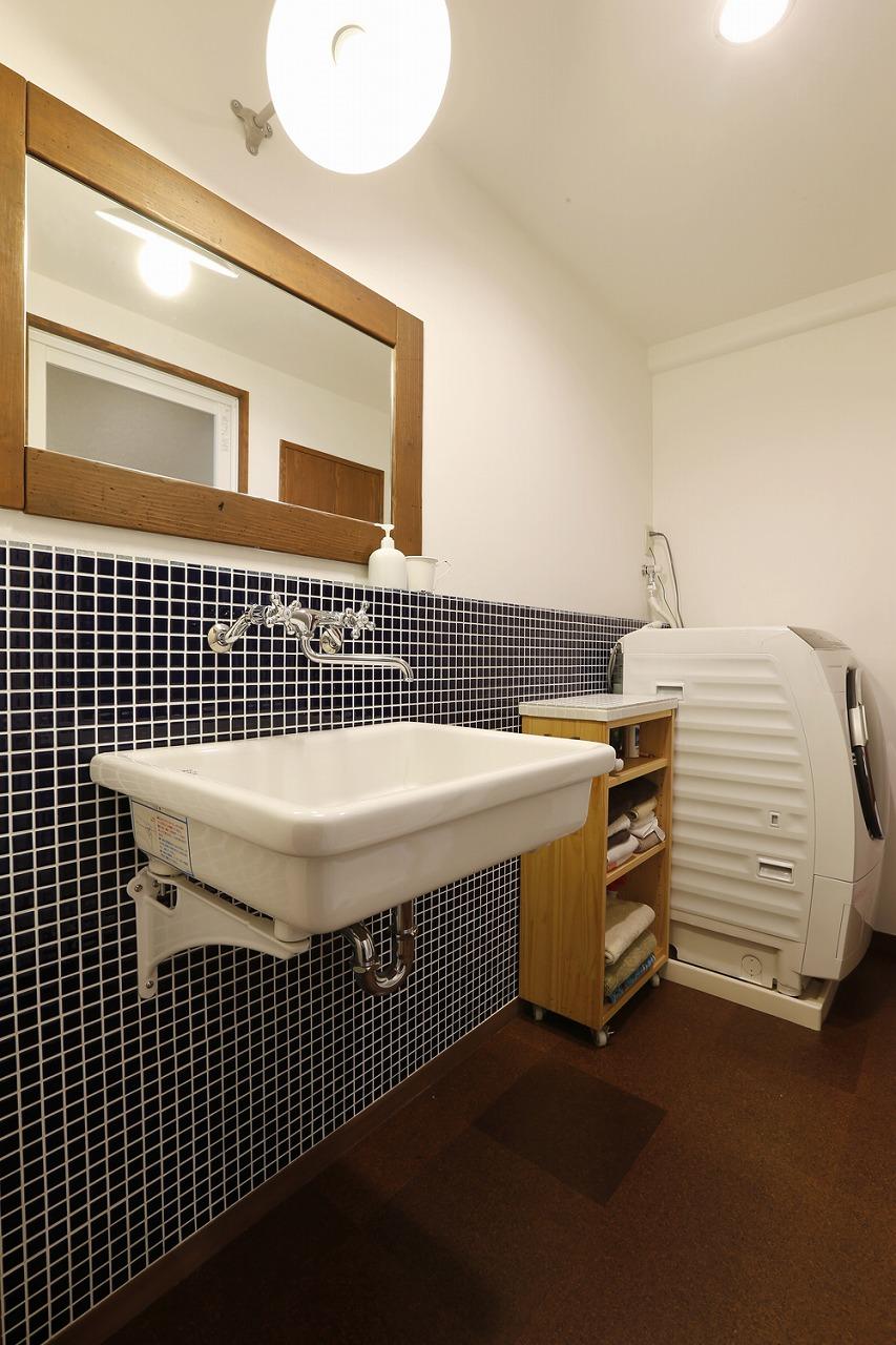 洗面室の壁は濃いブルーのタイルと白いクロスを使用