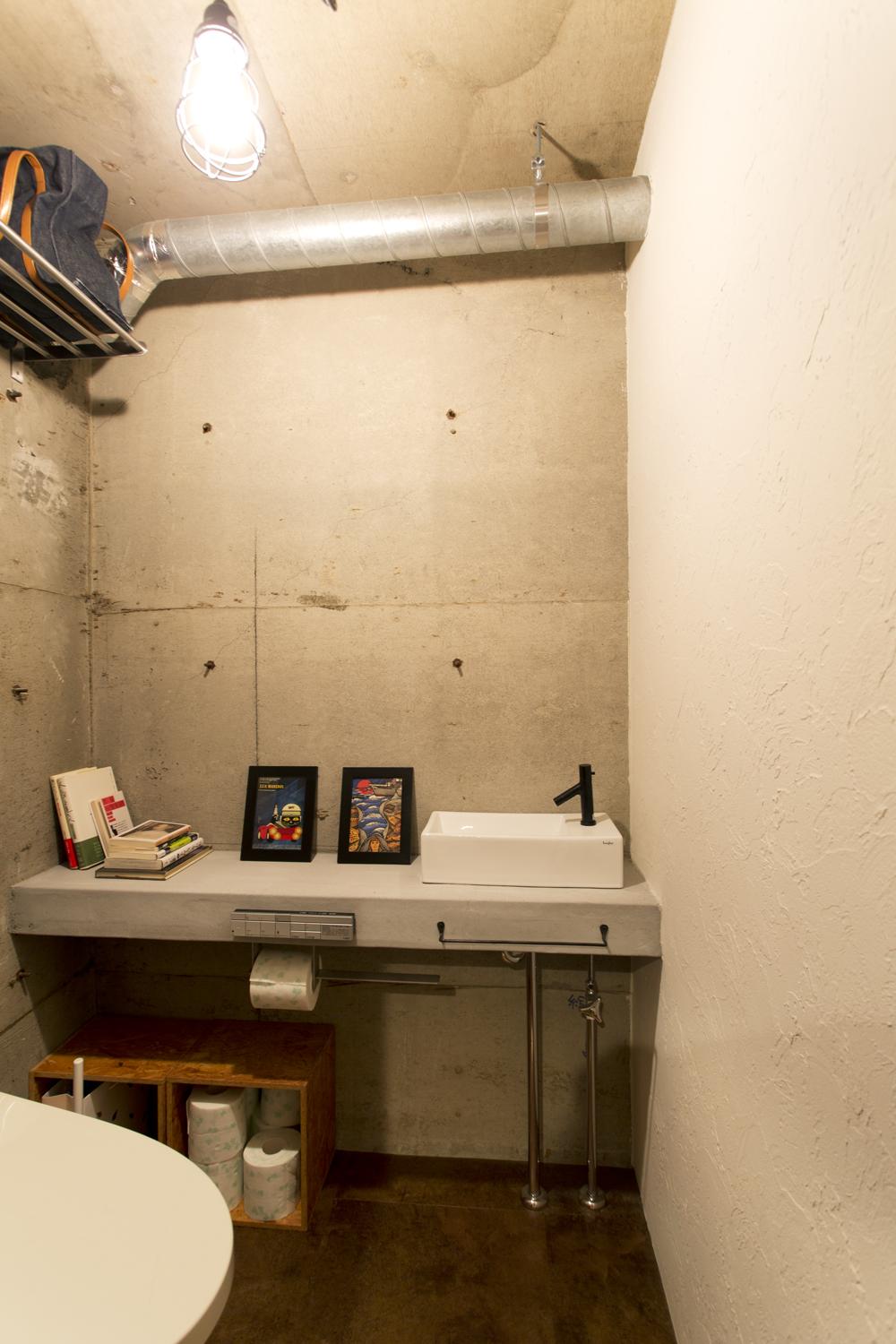 トイレの壁はコンクリートの躯体をむき出しに。右側の一面のみ調湿・消臭効果のある珪藻土を塗っています。手洗いカウンターは壁の雰囲気に合わせ、モルタル仕上げにしています