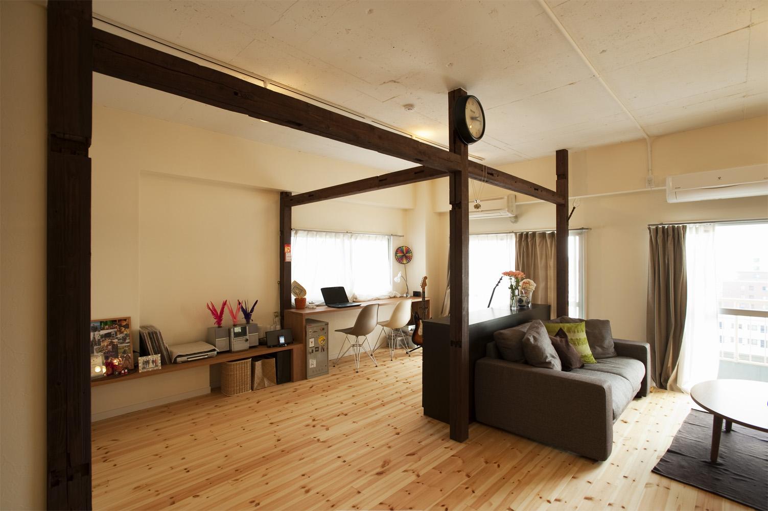 古材の柱と梁を使ってリビングの一部をゾーン分けしました。時計がかかった中央の柱からベランダ側は、カウンターデスクを造作して書斎スペースです。