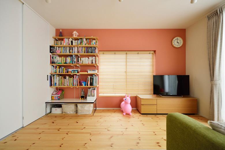 リビングの壁を一面だけサーモンピンクのアクセントクロスに。壁には家族共有の本棚を造作。可動棚になっていて、必要に応じて自由に棚の位置を変えることが出来ます。