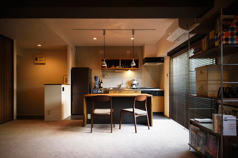 リビングと寝室の仕切りをなくした広々としたＬＤＫ。キッチンは既存のものを再利用。壁にタイルを貼ったり、上棚をなくしてオープンな造作棚を設けることで、雰囲気を一新