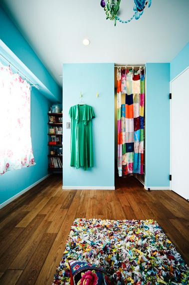 寝室はカラフルなシャンデリアが映えるよう、壁は薄いブルーに。ウォークインクロゼットは扉をなくし、出入り口にはUさんお手製のカーテンを。左手奥は、雑貨や紙製品などを収納するスペース。雑然と見えないよう奥まったところに棚を作っています。