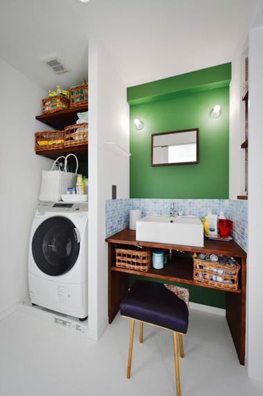 洗面台はキッチンの収納棚と同じ、濃いグリーンとこげ茶の組み合わせの造作洗面台。シンク周りに水はね対応のためのタイルをライン上に入れることで、空間のアクセントにも