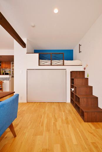 元和室の押入れだった部分は、上部をベッドにして一人分の寝室スペースに。ベッドの手摺りはTさんが気に入って購入していたアイアンに合わせて設計しました。壁はブルーのアクセントクロス。ベッドに上がる階段は、内部を本棚として使えるように造作しています。ベッドの下は大容量の収納スペースとして活用。
