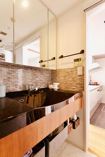 リフォームのきっかけとなった洗面カウンターも設備を一新。黒のシンクに木目のデザイン。壁のタイルは洗面台の雰囲気に合わせてTさんが選んだものを採用しました。床は水まわりのお手入れがラクなフロアタイルです。