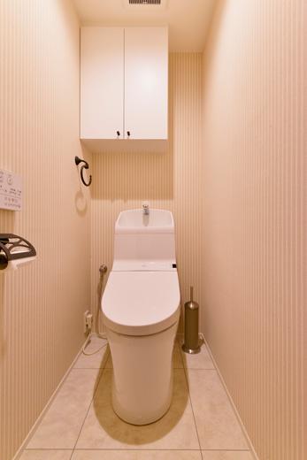 トイレの設備も一新。上棚は既存のまま、取っ手のみ黒の塗料を塗りイメージ一新。床はお手入れの楽なフロアタイル。壁はシンプルなストライプのクロスで上品に。