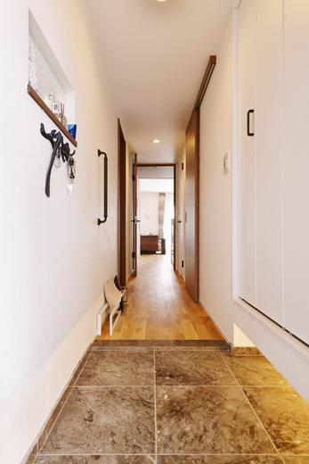 カウンタータイプの下足収納を撤去し、新しく大容量の下足収納を造作。カギなどを置く場所が欲しいというご希望により、下足収納と反対の壁にニッチを設けました。玄関の床のタイルも新しくして雰囲気を変えています。