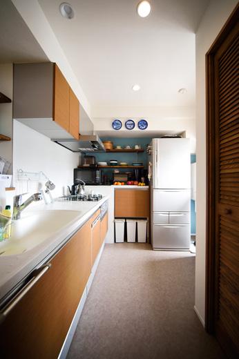 キッチンは配置を変え、料理をしながらリビングが見渡せるように。以前、キッチンがあった壁面には収納棚を造作。ダストボックスがすっきり収納できるようにしている。冷蔵庫の右手は室内給湯器があり、それを組み込んだデザインの家電収納を造作した