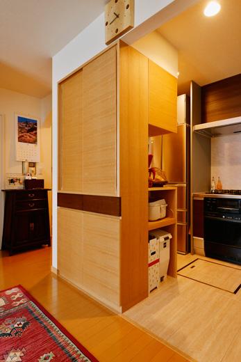 リビングとキッチンの間には、3面から使える造作収納を。リビング側は食器やカトラリーを収納できる。扉は柾目のナラ材。上部は引違い戸、中央は引き出し、下部は開き戸と収納するものによって便利に使えるように。キッチン側の2面は実際に使っている家電の大きさに合わせて設計した家電収納となっている