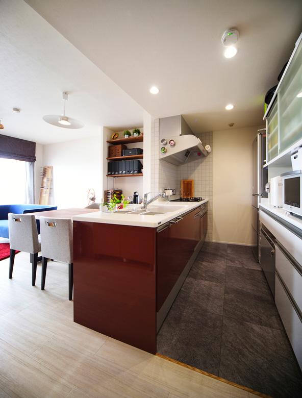 キッチンはフラットなオープンキッチン。上棚をなくし、より開放的で明るい空間となった。コンロ周りの壁はタイルを。食器棚は既存のものを採用。床はフロアタイル。ダイニングの壁に造作した棚は、パソコンデスクとしても活用できる