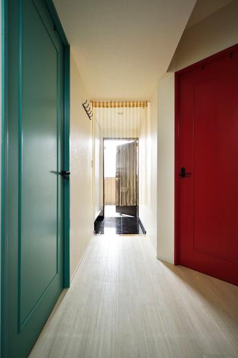 玄関を入ってすぐの左右の部屋は、2人のお子さんたちの個室。既存の扉を塗装して仕上げた。玄関から細長い廊下が伸びていた玄関ホールは、赤い扉を斜めにつけることで廊下を広げ、右手奥のウォークインクロゼットに直接出入りできるようにしている