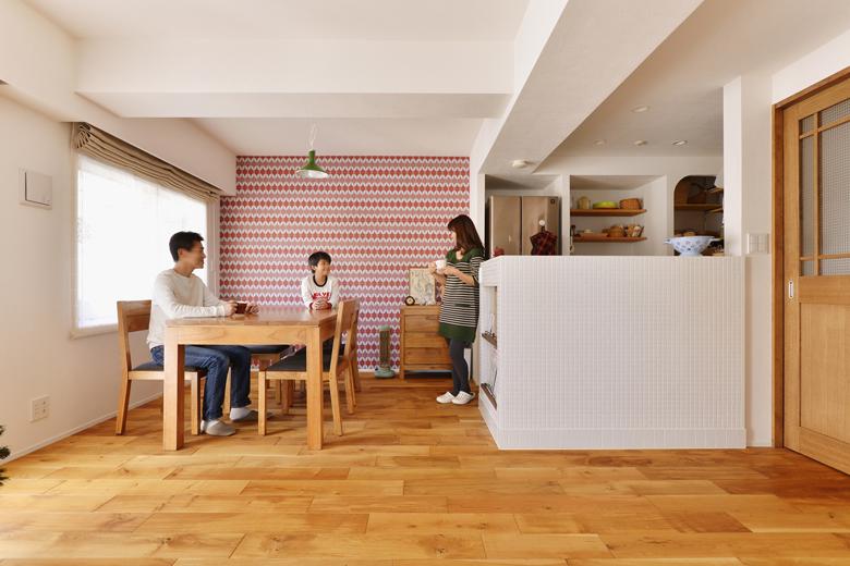 キッチンの壁をなくしてオープンにした、開放的なＬＤＫ。床は幅広のオーク無垢材。一枚一枚の長さが異なる乱尺タイプで、より無垢材の質感を楽しめます。建具はタモ材で造作したオリジナル。ダイニングの壁は一面のみ明るい色と柄の輸入クロス。Mさんが気に入って購入したものを取り入れました。