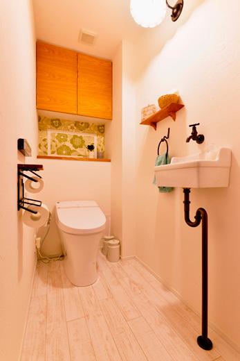 白を基調にした清潔感のあるトイレ。カウンターの壁はMさんが選んだ輸入クロスを。吊戸棚は扉のみ造作しました。トイレと手洗いの設備も新しくして、デザイン面も使い勝手も向上。床はお手入れしやすいフロアタイルに。