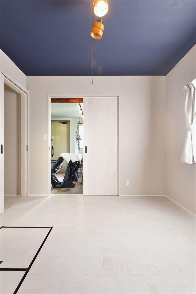 玄関横の和室は仕事場のスペースに。床はお手入れがしやすいよう、木目調のフロアタイルに。壁は落ち着いたブルーグリーン色で塗装した。隣の寝室とは引戸で仕切ってあり、必要に応じて開け閉めして小さなお子さんの様子を確認できる