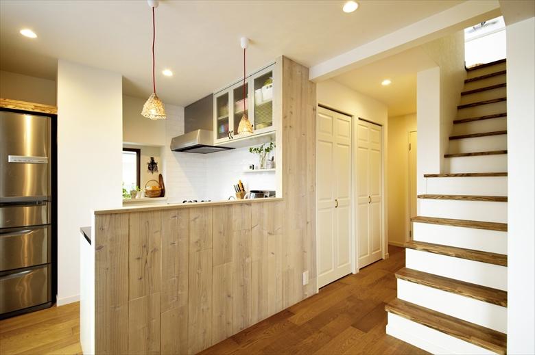 対面式のキッチンにはカウンターを造作。キッチンの照明の雰囲気に合わせ、カウンターはざっくりとした足場材を白く塗装して貼った。