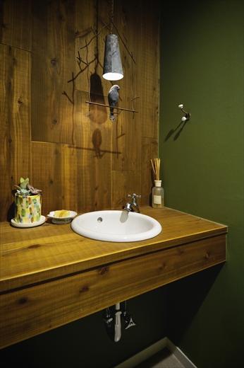 トイレは鳥をモチーフにした照明を使いたいというご希望により、手洗いカウンターは足場材で木の雰囲気をたっぷりと。壁は深いグリーンで森林を思わせるイメージに