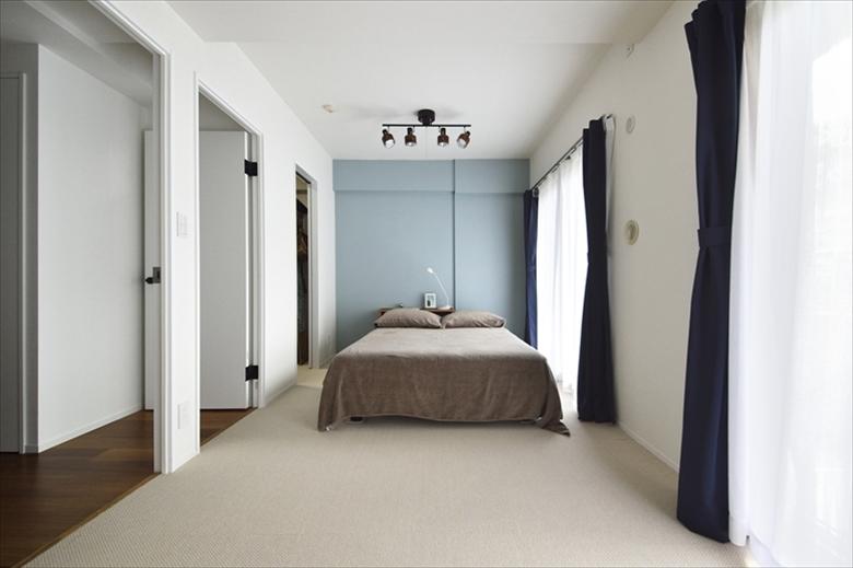 洋室2部屋の仕切りをなくした寝室。床のタイルカーペットと壁のブルーの面の塗装は、Sさんの希望により、ご自身で仕上げた。将来、お子さんが2人生まれたときのために、2部屋に分けられるようドアは2カ所設けている