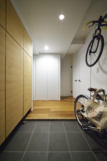 玄関は、隣の洋室の部分までスペースを広げ、Sさんの趣味である自転車を置けるように。下足収納は既存の収納棚に、扉のみタモ材で造作して雰囲気を一新。