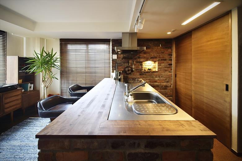 食事をするカウンターはキッチンの高さと合わせ、通常のダイニングテーブルより高く。ハイチェアーを合わせ、バーカウンターの雰囲気を演出しています。木製のカウンターの側面やキッチンの壁にはアンティークな素材感のあるレンガを使い、温かみのあるデザインとなりました。