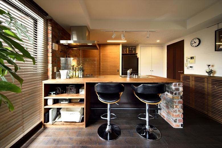 造作のカウンターは、キッチンの高さと合わせて少し高めに。ハイチェアーを合わせ、バーカウンターの雰囲気を演出。リビング側にはオープンな収納棚を設けた。カウンターの側面はラフなイメージのレンガを採用