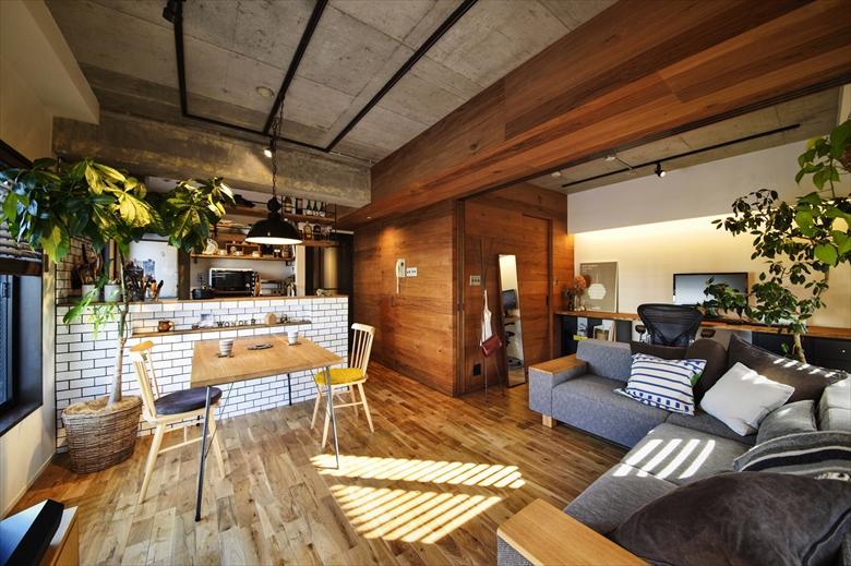 リビングと和室を一体化して広々としたＬＤＫ。床はオーク無垢材、壁の板貼りはブラックチークのパネル。天井はコンクリートの躯体を現しにして、素材の質感の違いを楽しめます。