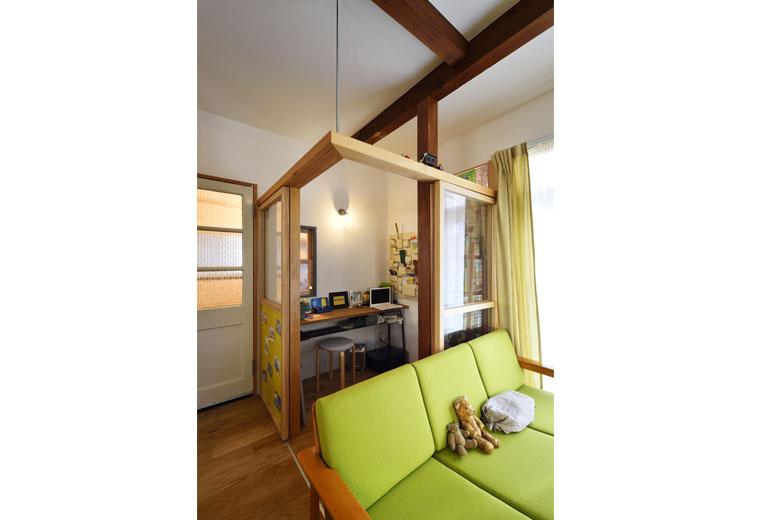 リビングの一角につくった、奥様の仕事スペース。普段は開け放して開放的に。閉めてもガラス戸で視線が抜けるため、開放感を損なうことなく、落ち着いて仕事ができる。建具は天井まで塞がない高さにすることでリビングのエアコンの空気が入り、快適に過ごすことができる