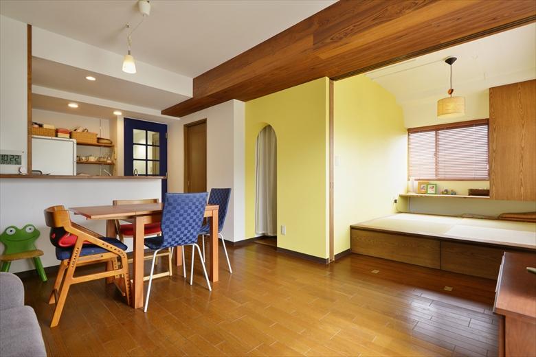 リビングは和室と一体化。和室部分は一部小上がりに。３枚引き込み戸で仕切ることもできる。和室隣の黄色の箱型になったスペースはウォークインクロゼット。対面式のキッチンは吊戸棚をなくし、リビングとつながるオープンな空間に。リビングに入るブルーの建具は、既存のものを塗装して雰囲気を一新した。