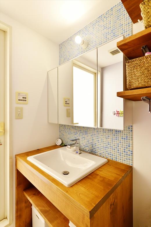 洗面カウンターは、同社の施工事例を参考に造作したオリジナル。壁は好きなブルーを基調にしたモザイクタイルに。鏡に映っている洗面カウンターと反対側の壁は、少しくすんだブルーに。甘くなり過ぎないようにしつつ柔らかな雰囲気のブルー系でまとめた。