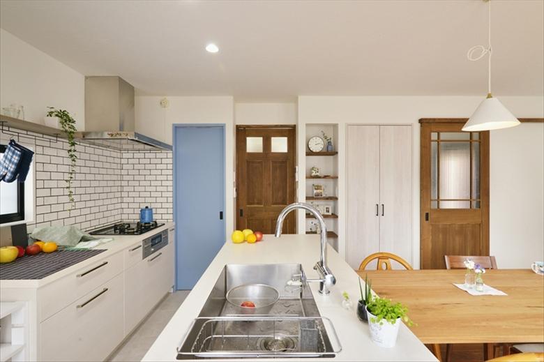 キッチンはセパレートタイプに。シンクの部分はアイランドになっており、家族で料理をするのに便利な使いやすいキッチンだ。キッチンの壁は「違う質感にしたい」という希望によりタイル貼り。コンロの奥は収納力たっぷりのパントリー。内部の壁は珪藻土。扉はIさんの好きな明るいブルーで塗装した。