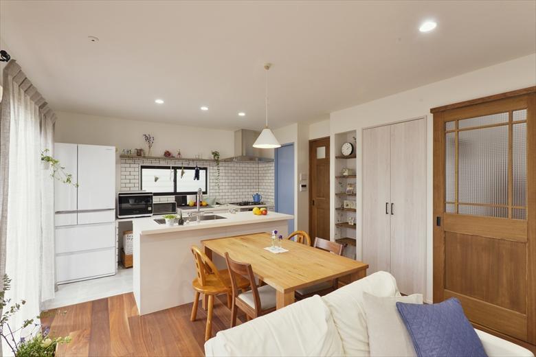 袖壁と下がり壁で仕切られた印象だったキッチンとリビングは、壁の凹凸をなくして一体化。開放的なＬＤＫとなった。リビングの床は床暖房に対応したウォールナットの無垢材。天井は珪藻土仕上げ。リビングには扉付きの収納とオープン棚を設け、すっきりと片付けられるようになった。