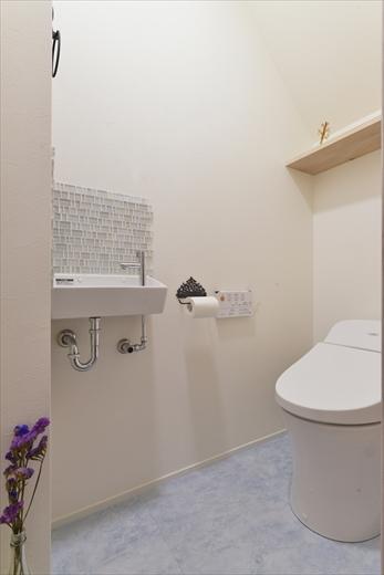 夫人と娘さんで「お姫様」をテーマにデザイン。床はアイスブルーのフロアタイル。手洗いシンクの前の壁には、ガラスをイメージしたタイルを貼った。背面の木製の固定棚も白く塗装して雰囲気を統一。大人っぽい雰囲気の中にかわいらしさも感じられる空間。