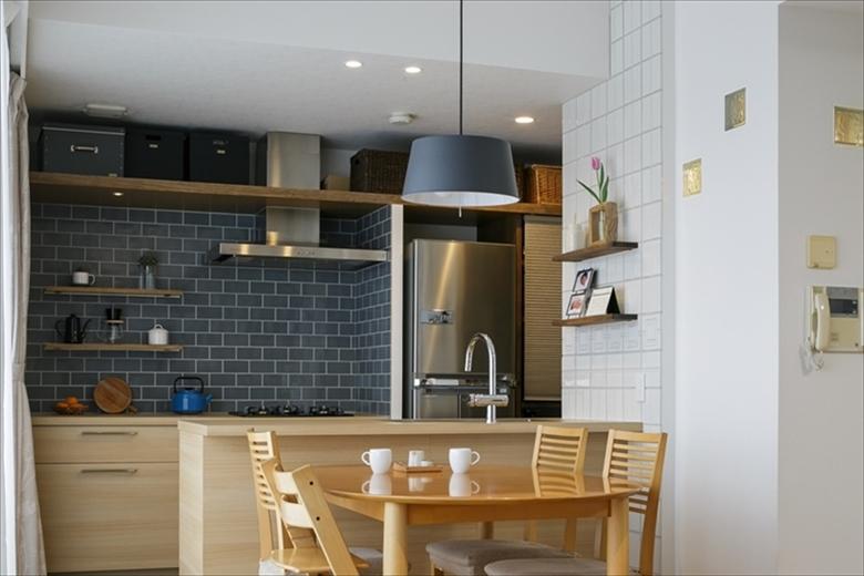 壁と収納家具で仕切られていた壁づけのキッチンは、セパレートキッチンに変えてオープンに。天井高を生かし、キッチンの壁にも天井下に収納棚を造作。手前の白い壁の裏は洗面室。ガラスブロックから光が入るように。