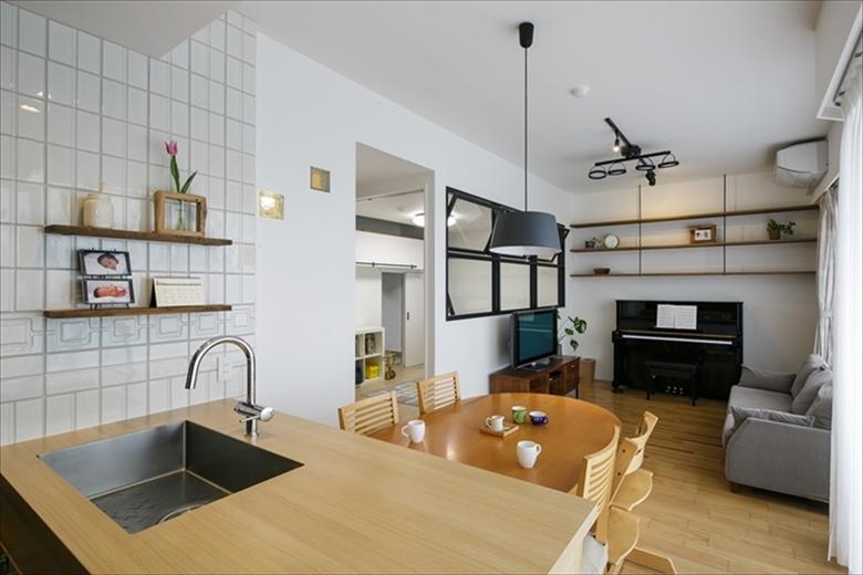 バルコニーからの光がたっぷり入る明るいリビング。間取りはそのままで和室だった部分を壁で仕切り、子ども部屋に。壁には開閉できる室内窓を設け光と風を通しつつ、キッチンやリビングから子ども部屋の様子を見守ることができる。もともと天井高がある住まいだったためピアノの上の空間にあえて飾り棚を造作。