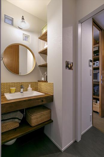 洗面カウンターは造作。収納棚は、もともとリビングの収納だったスペースを洗面室から使えるように作り変えたもの。壁にはガラスブロックを入れ、リビングからの光が入るようにした。