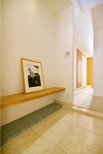 玄関は、隣の洋室の一部を取り込んで広げたことで一部床に段差が出たが、グリーンのタイルを貼ってアクセントに。日常使いの靴を置くスペースとして活用できる。Tさんご希望のベンチは、腰掛けたりモノを置いたりするのに便利