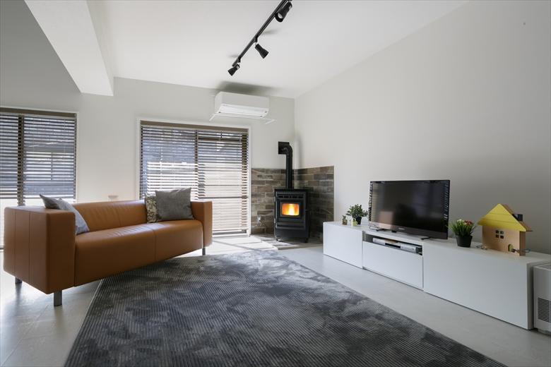 リビングは日当たりが悪くて暗い1階から2階に移動。和室、洋室、階段室の間仕切りをなくして一つのＬＤＫを実現した。床のコルクタイルと壁は白を基調に、照明やペレットストーブの濃い色が差し色となってモダンな印象に。リビング階段の吹抜けも、ペレットストーブにより暖かく過ごすことができる