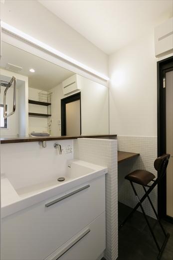 1階の洗面室。洗面カウンターの隣には夫人の化粧用のデスクを造作。そのために鏡をデスク前まで広げた。背面には洗濯機とトイレを。一つの空間を多目的に使えるホテルのサニタリーをイメージした