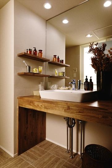 シンプルな洗面カウンターはタモ材で造作。大きな鏡は既存のものを再利用。床はお手入れしやすいフロアタイルに。