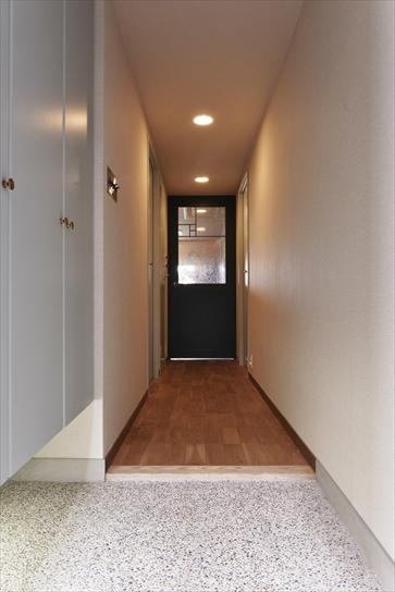 玄関の土間は金華砂利と貝殻を埋めた洗い出し仕上げ。廊下はリビングと同じナラ無垢材。下足収納は既存のものをそのまま残し、扉のみ塗装して雰囲気を変えた。