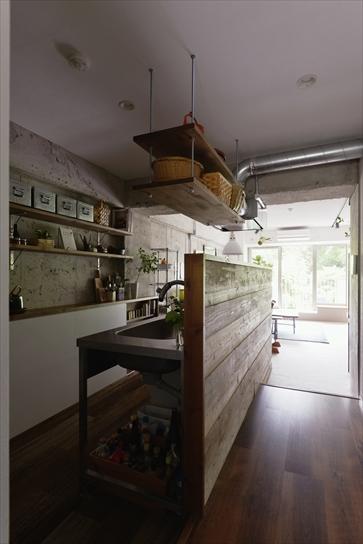 独立していたキッチンは位置を移動して、リビングとつながるオープンキッチンに。カウンターは足場板で造作。廊下は床下に配管があるために一段高くなっている。キッチンで作業する手元が隠れるよう、カウンターは高めに設計