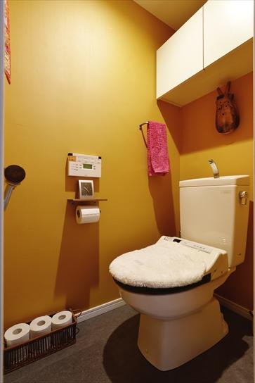 トイレの設備、白い収納棚は既存のまま。壁をアースカラーのクロスに変えることで、落ちついた雰囲気に一新した