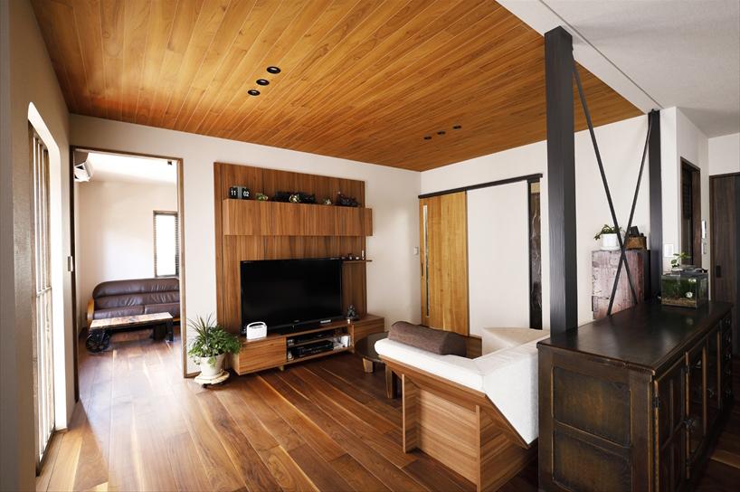 1階親世帯のリビング。もともとのリビングに和室と納戸の間仕切りをなくして一体化し、広々としたLDKの空間を実現した。床はお母さまのご希望によるウォールナットの無垢材。天井のどこかを板張りにしたいというご希望は、元和室の天井で叶えた。木製のテレビボードは、キッチンと同じ製品で統一感を。