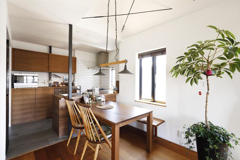 2階子世帯のダイニング・キッチン。キッチンはL字型。オープンな対面式で料理をしながらお子さんの様子を見守ることができる。収納カウンターの上には吊り収納を造作し、収納力もアップ。壁は白いタイルでさわやかな印象に。ダイニングの天井はあけて吹抜けにし、開放感を。