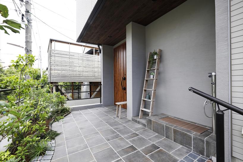 親世帯用、子世帯用と2つに分かれていた玄関は1つに。以前、親世帯用の玄関ドアがあった部分は、愛犬の足洗い場として水栓とステップを。玄関ポーチもタイル貼りにして雰囲気を一新。道路側には植栽スペースを設けた。