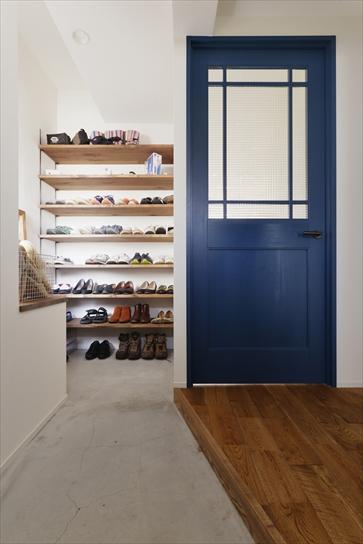 玄関の隣の洋室は、内部を分けてウォークインクロゼットとシュークロークに。シュークロークは玄関から土間でつながっている。壁にはたっぷり靴を収納できる可動棚を造作。手前には既存の洋室のカウンターを利用してベンチを。ブルーの建具はリビングの入口。Nさんの好きなブルーに塗装した。