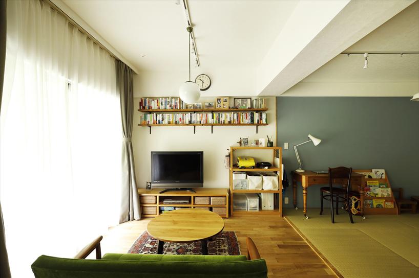 リビングは隣の和室との仕切りをなくしてフラットに。テレビを置いている壁のみ珪藻土で仕上げた。テレビの上には本などたっぷり収納できる可動棚を取り付けた