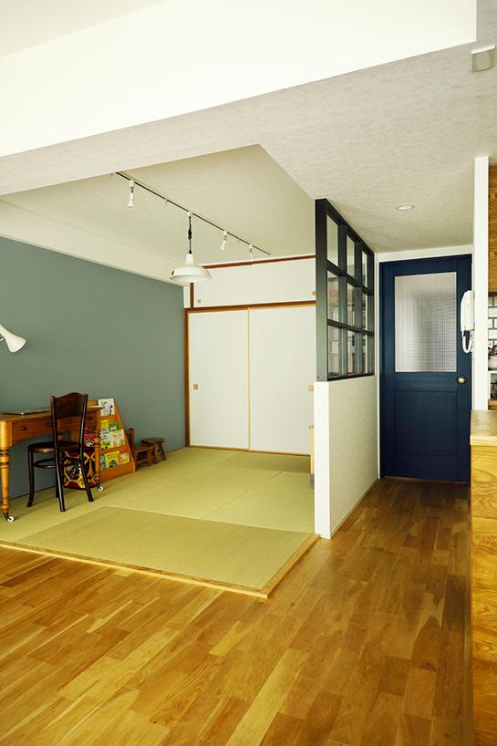 リビング隣りの和室は、仕切りの壁をなくしてリビングと一体化。室内窓を取り入れたいというご希望により、一部壁を残して室内窓を造作した。壁は一面のみグレーのアクセントクロス。押入は既存のまま、建具のみ張り替えて雰囲気を変えた。リビングに入るドアは木製のGPドアに、Yさんが好きなブルーで塗装した