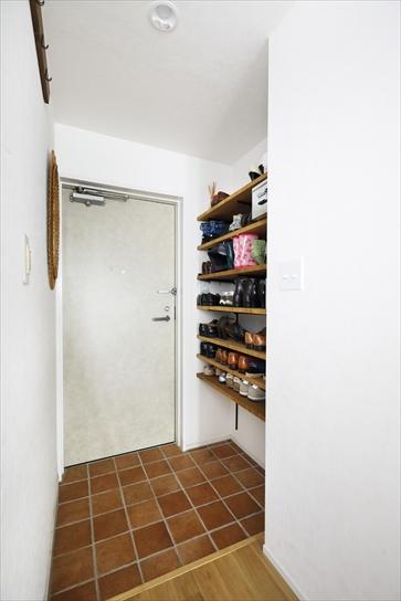 玄関はカウンタータイプの下足収納があったが、撤去してオープンな収納棚を造作。より収納力をアップさせた。床はタイル貼り